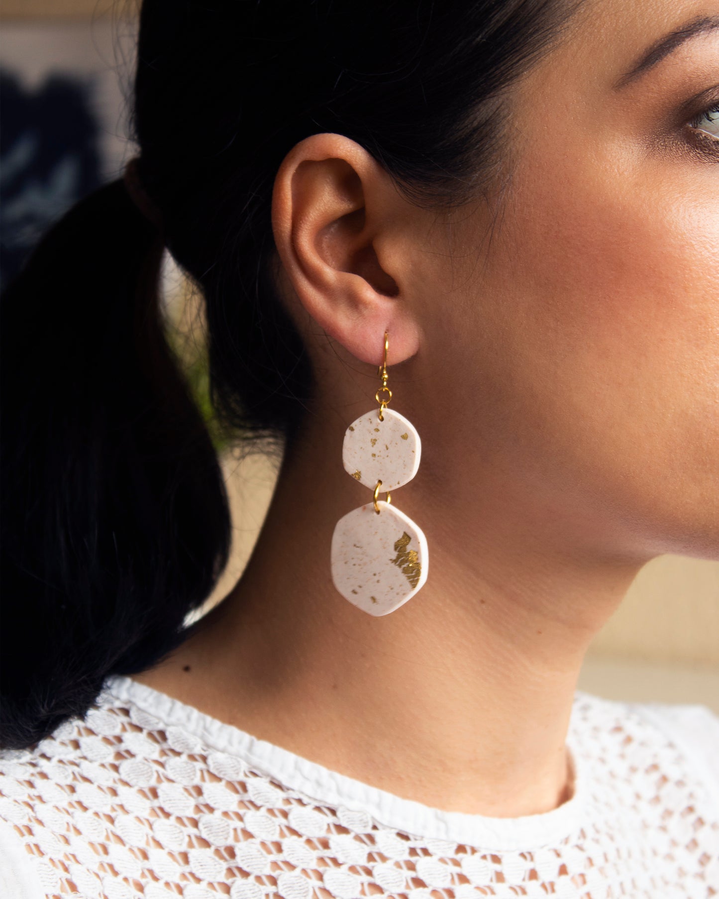 Model wearing handmade white and gold leaf boho earrings, showing their elegant drop length and lightweight design.