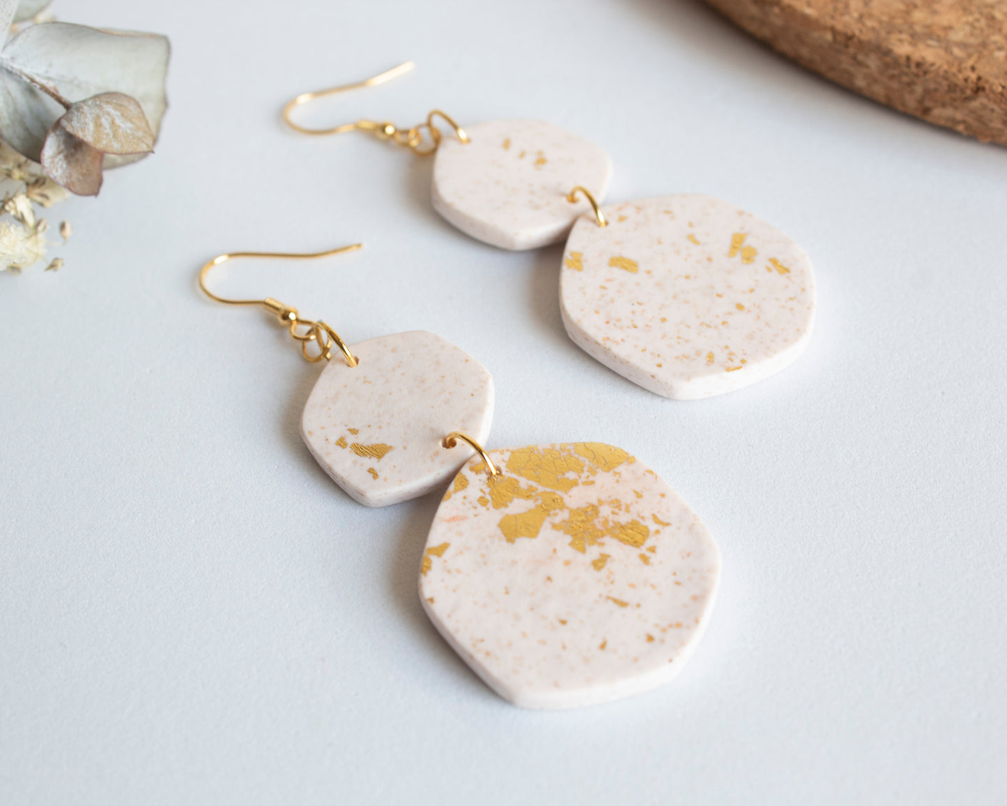 Detail shot of white and gold leaf boho earrings laid flat, showcasing the handcrafted geometric shapes and texture.