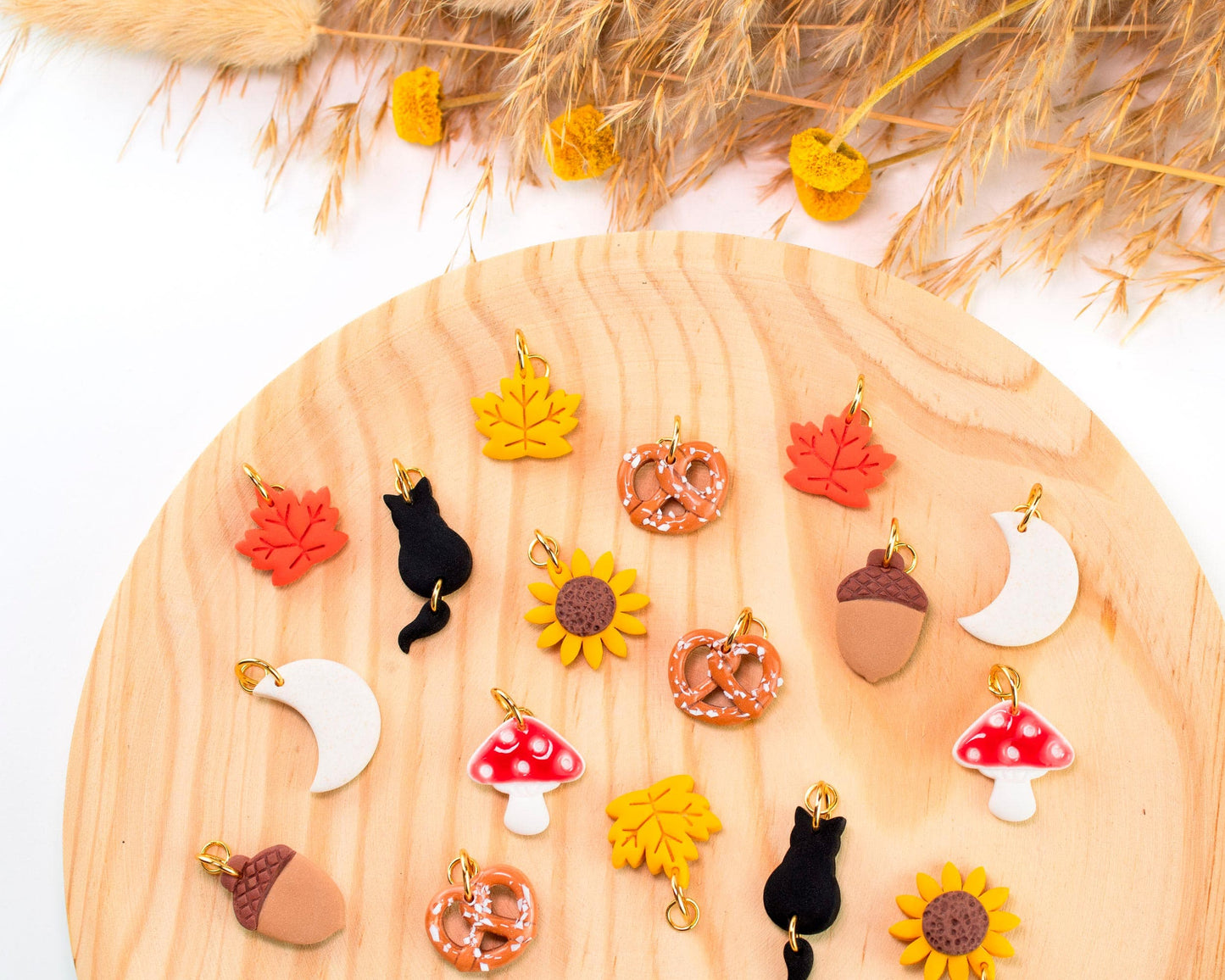 Handmade polymer clay fall charms for hoop earrings, including leaves, sunflower, pretzel, mushroom, and cat. Cute autumn-themed charms.