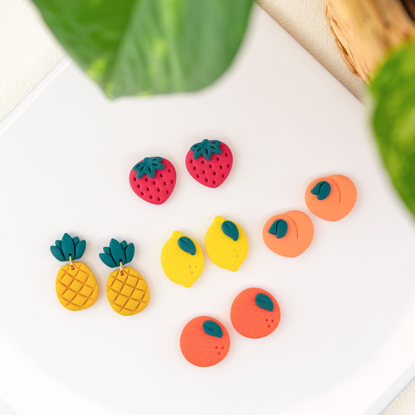 Fruit stud earrings handmade in clay featuring strawberry lemon peach orange and pineapple