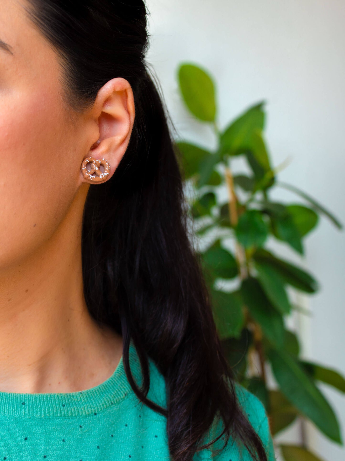 Handmade pretzel stud earrings worn by a model, showcasing their size and realistic design.