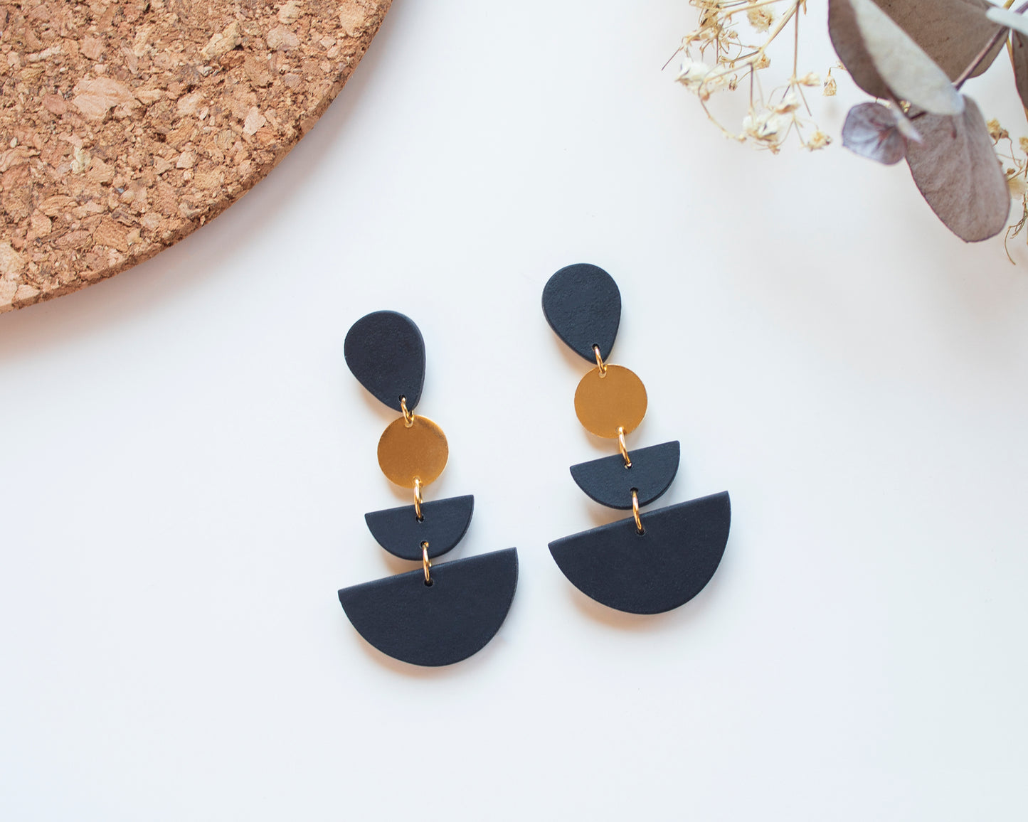Handmade black geometric earrings with a minimalist design, featuring gold details and 925 sterling silver posts.