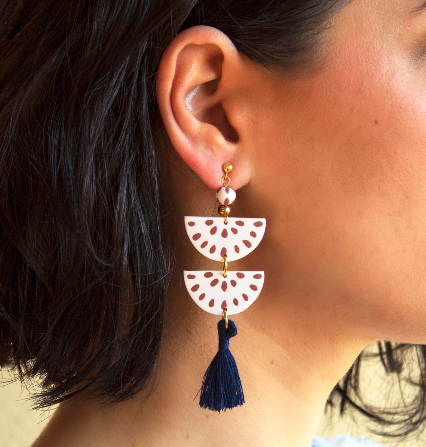 Model wearing handmade clay earrings in navy and cream with boho tassels