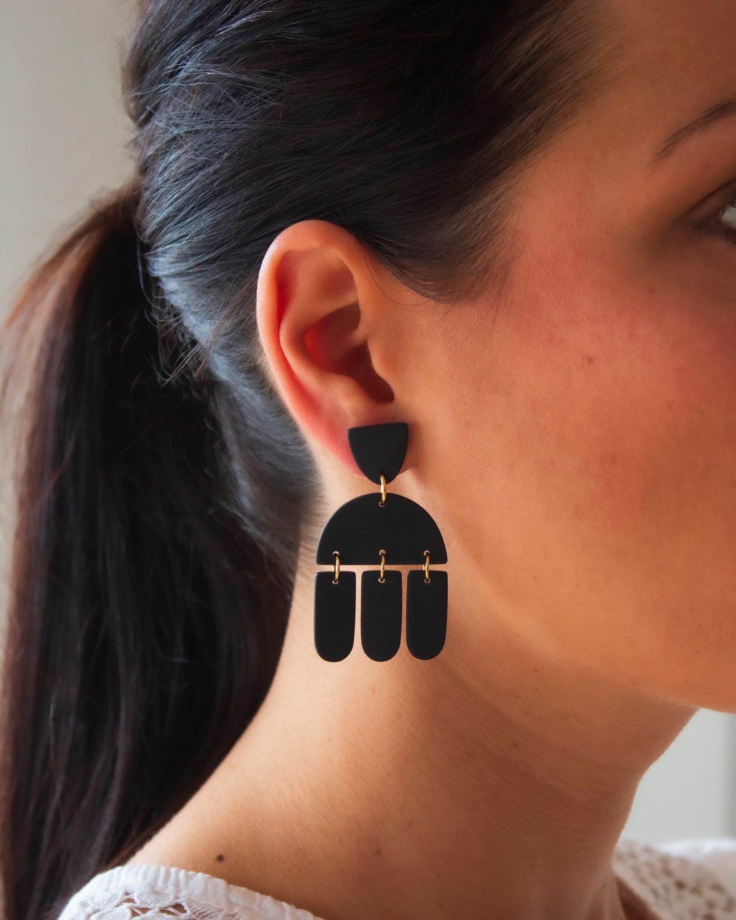 Model wearing long, geometric, boho style black earrings.