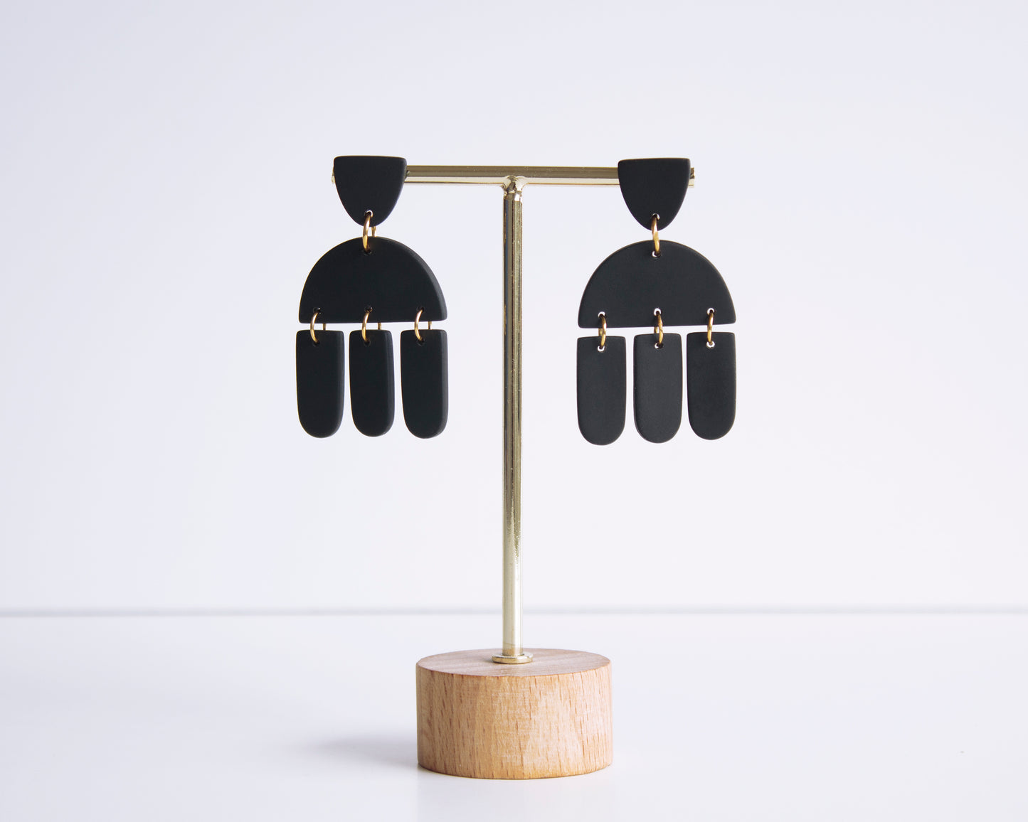 Black geometric earrings displayed on a stand, handmade with polymer clay, perfect for boho style and lightweight wear.