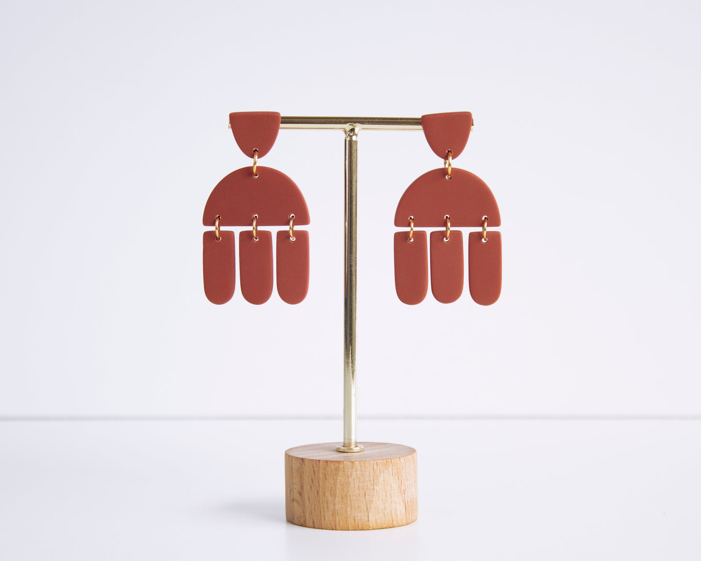 Terracotta geometric earrings displayed on a stand, handmade with polymer clay, perfect for boho style and lightweight wear.