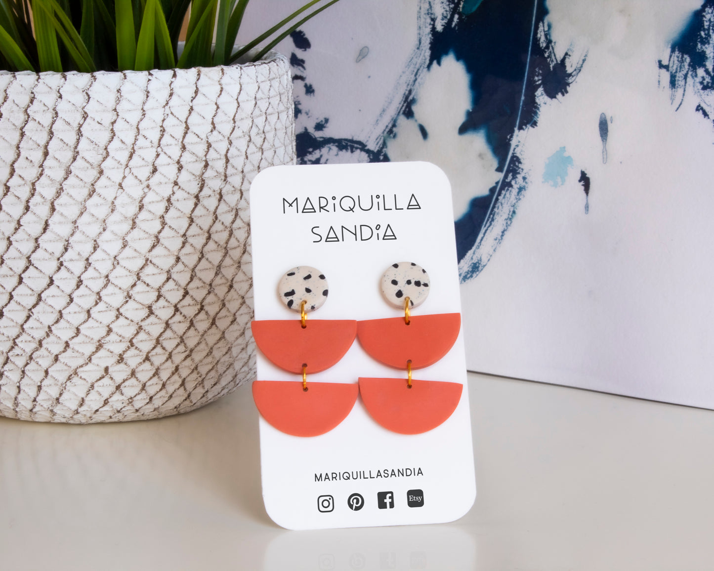 Coral and black boho dangle earrings with Mariquilla Sandia branding.