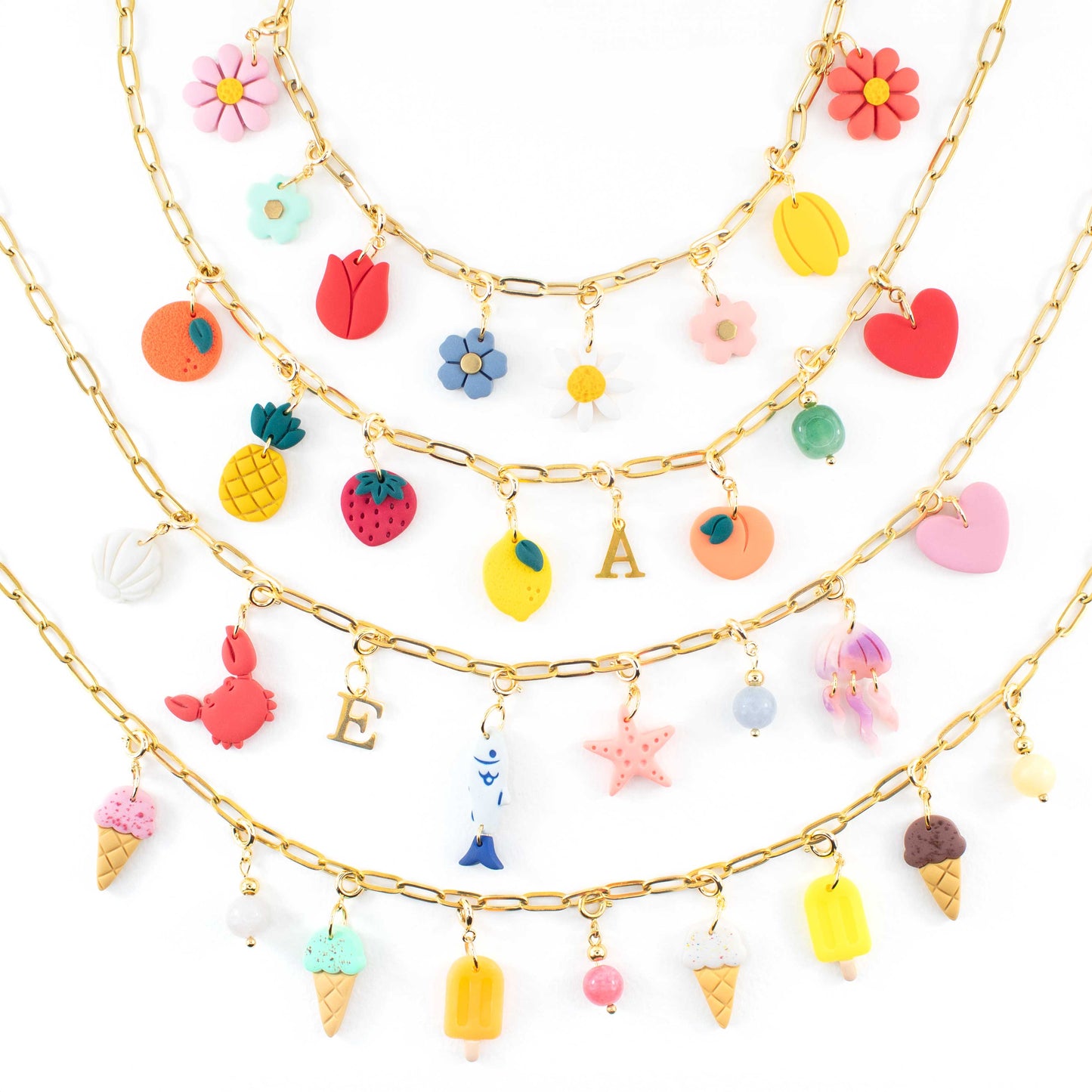 Custom charm necklace with interchangeable handmade clay charms in flower, fruit and initial designs, shown on a gold plated chain