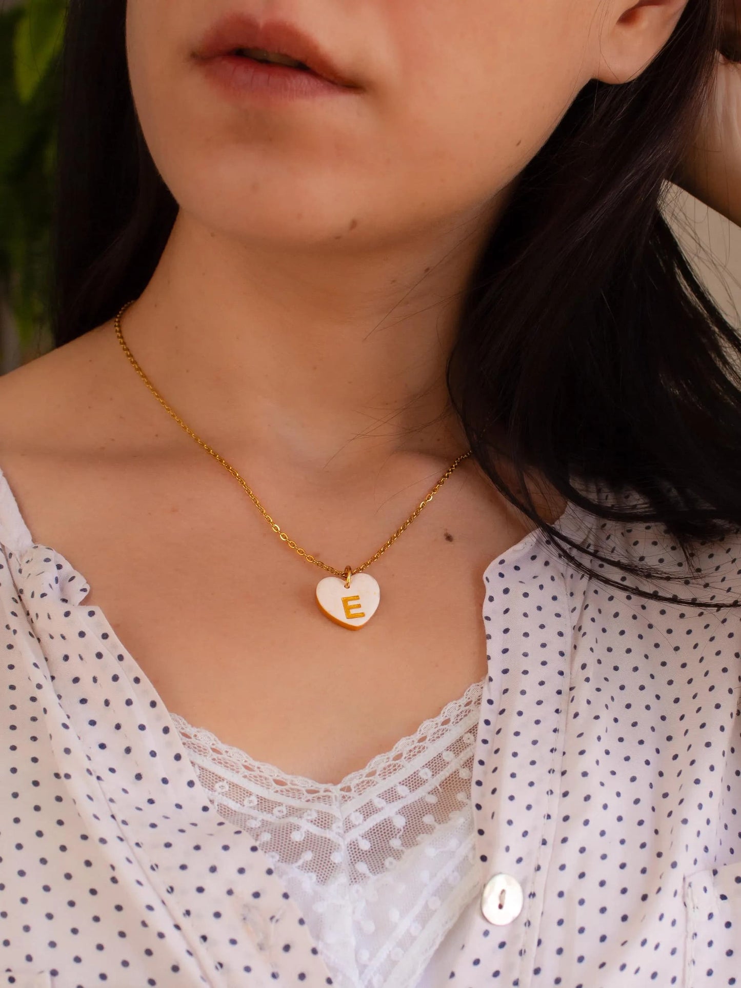 Model wearing personalized heart initial necklace in white blouse