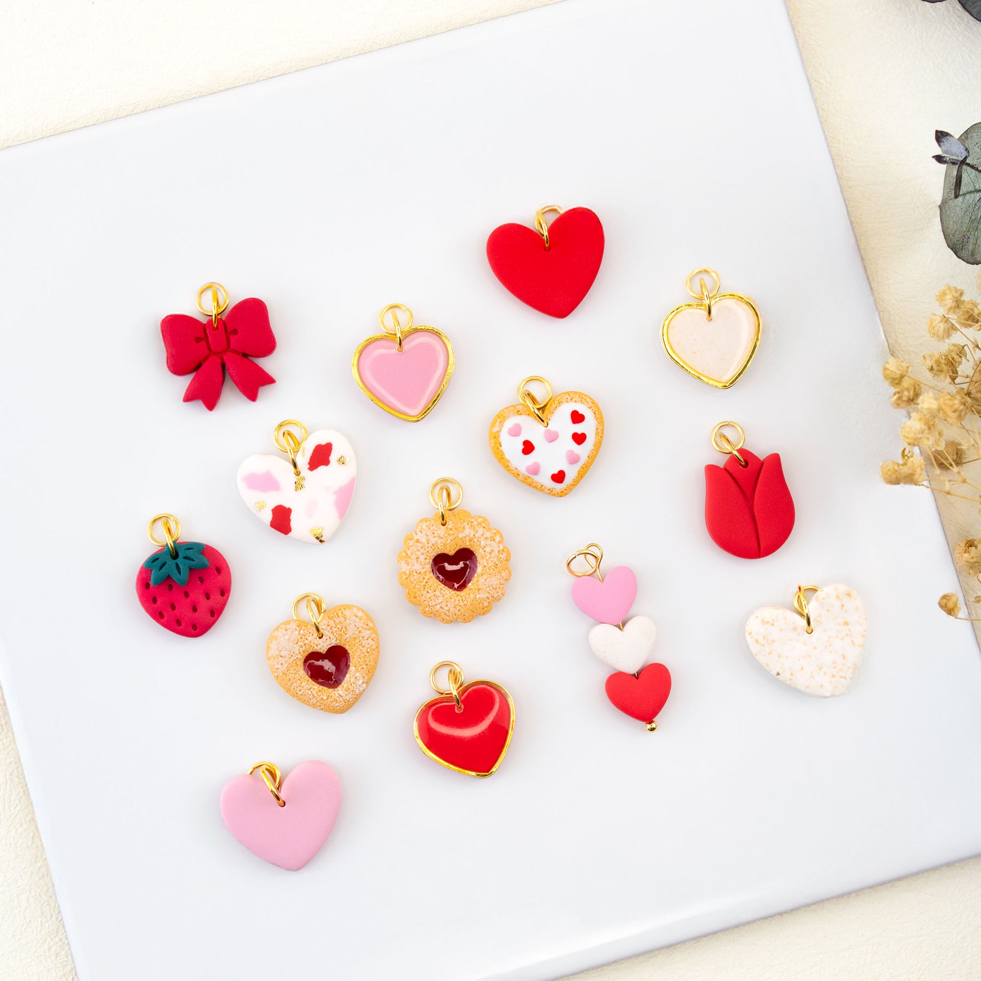 Flat lay of handmade Valentine charm earrings with cookie heart bow and strawberry charms