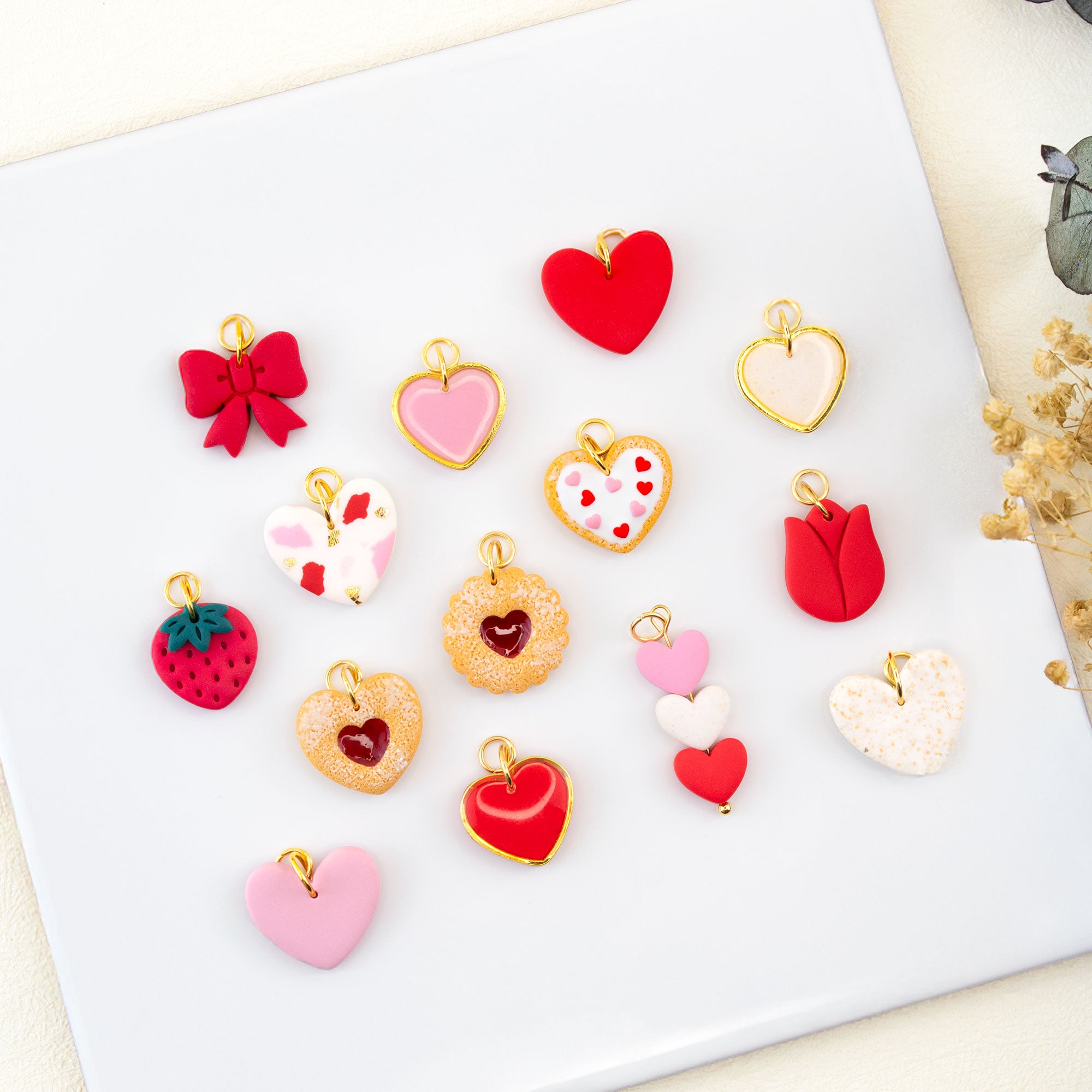Flat lay of handmade Valentine charm earrings with cookie heart bow and strawberry charms