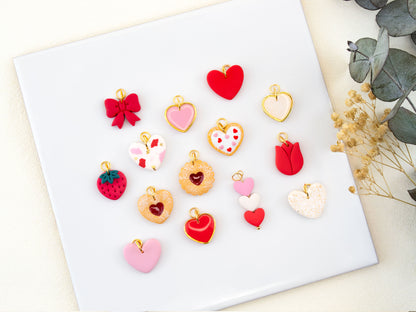 Flat lay of handmade Valentine charm earrings with cookie heart bow and strawberry charms