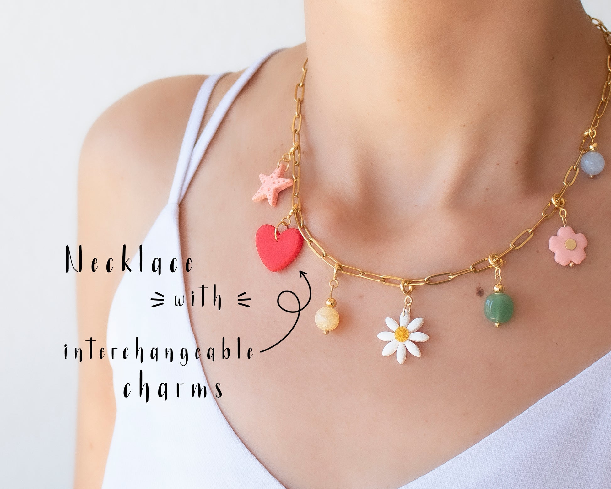 Close-up of a personalized necklace with interchangeable charms including initials, flowers, fruits and natural stones, displayed on a jewelry bust