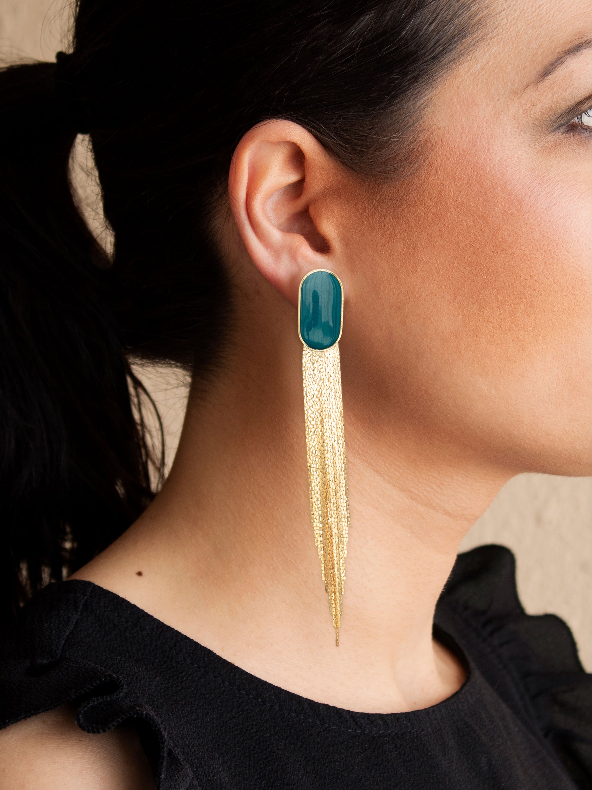 Green stud earrings with detachable gold chain fringe worn on ear