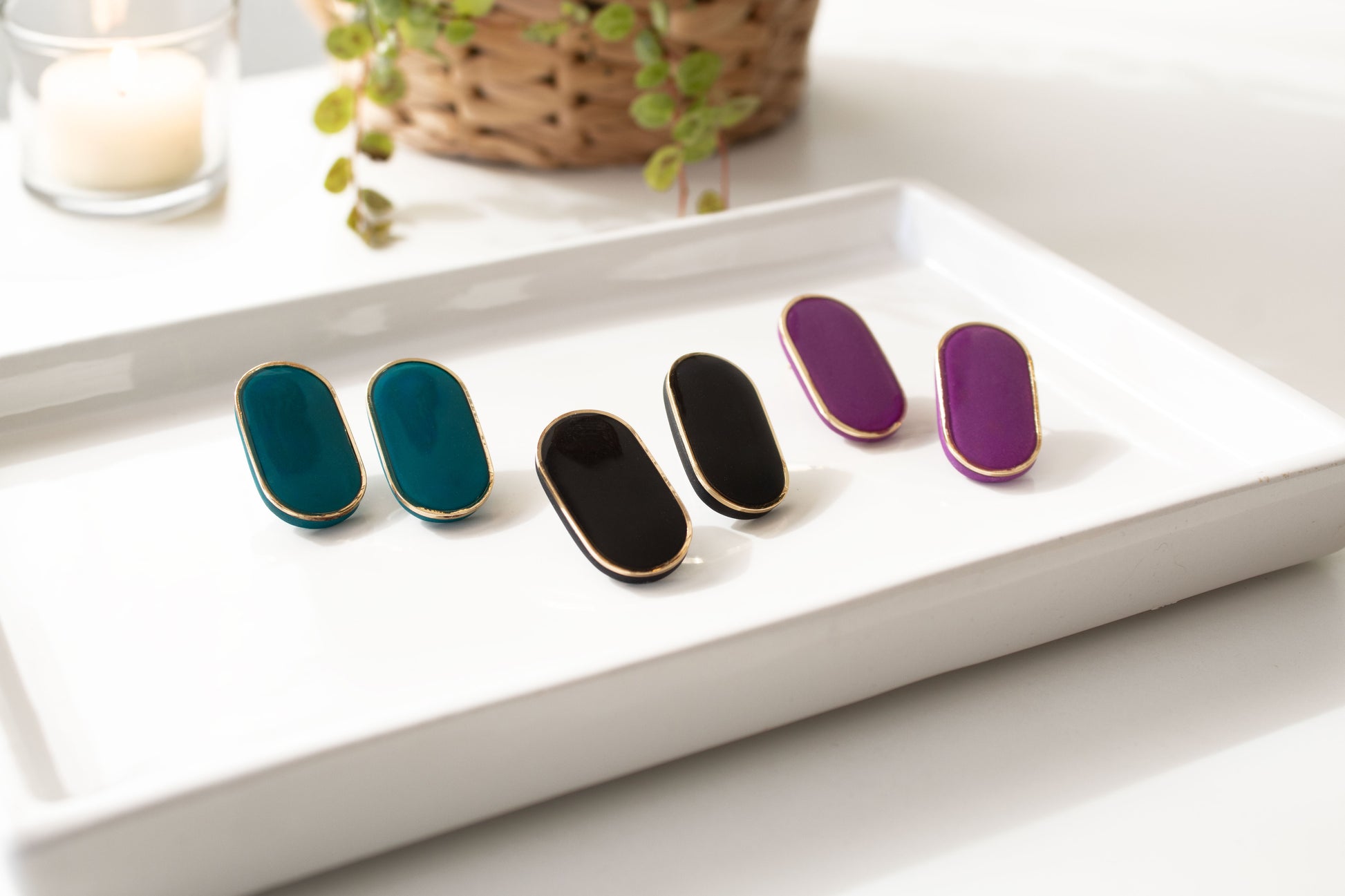 Geen black and purple stud earrings displayed on ceramic tray