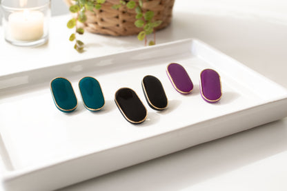 Geen black and purple stud earrings displayed on ceramic tray