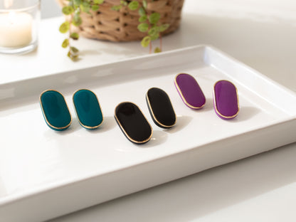 Geen black and purple stud earrings displayed on ceramic tray