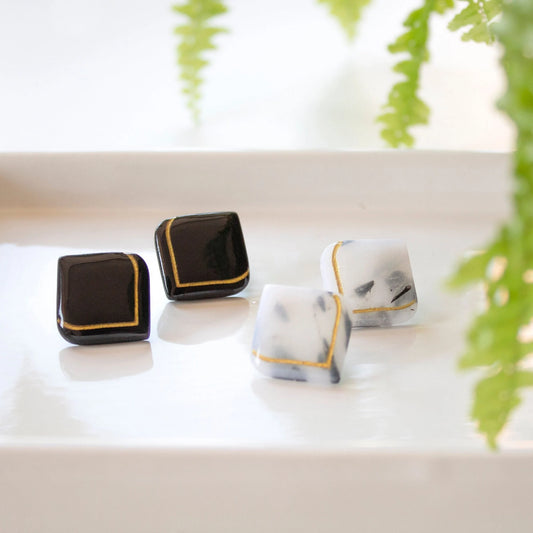 Handmade Art Deco stud earrings in black and white clay with golden detail