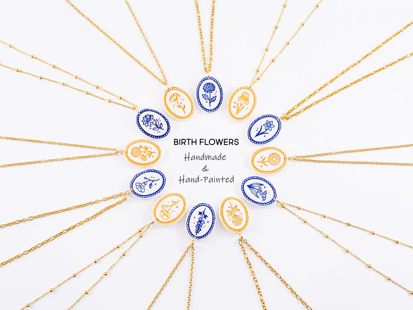 Twelve hand-painted birthflower necklaces arranged in a circle, alternating in gold mica and cobalt blue finishes. These hypoallergenic gold botanical pendants surround central text reading "Birth Flowers Handmade & Hand-Painted". A beautiful custom birth month charm collection and the perfect personalized jewelry for mom
