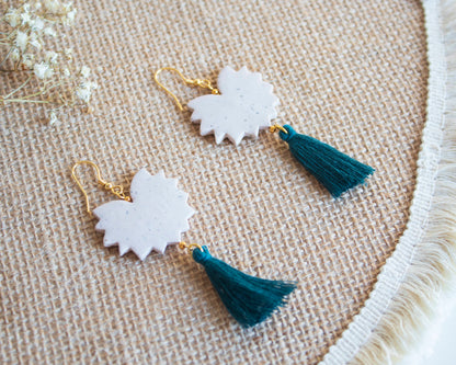 Handmade clay earrings with tassels, cream color, laid on a woven mat.