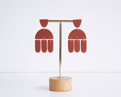 Terracotta geometric earrings displayed on a stand, handmade with polymer clay, perfect for boho style and lightweight wear.