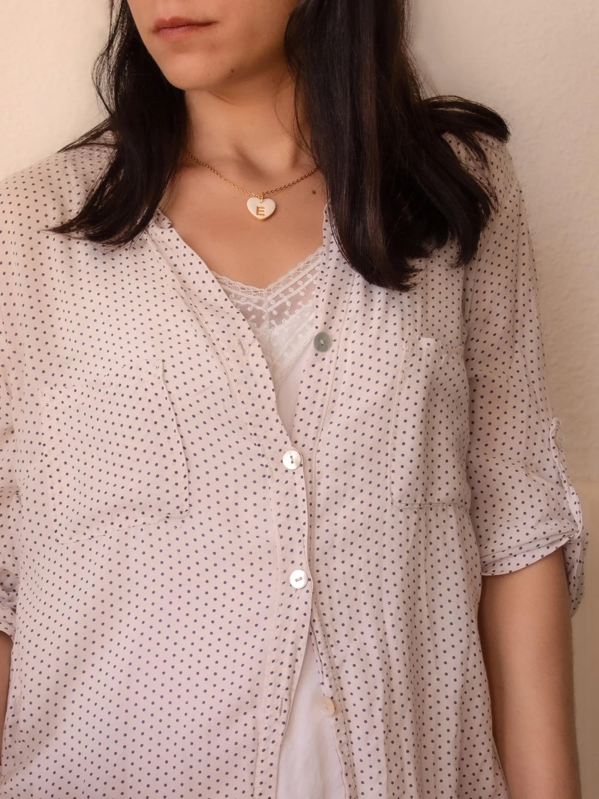 Model wearing personalized heart initial necklace in white blouse
