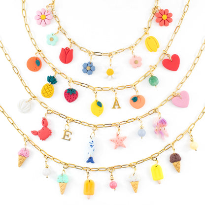 Custom charm necklace with interchangeable handmade clay charms in flower, fruit and initial designs, shown on a gold plated chain
