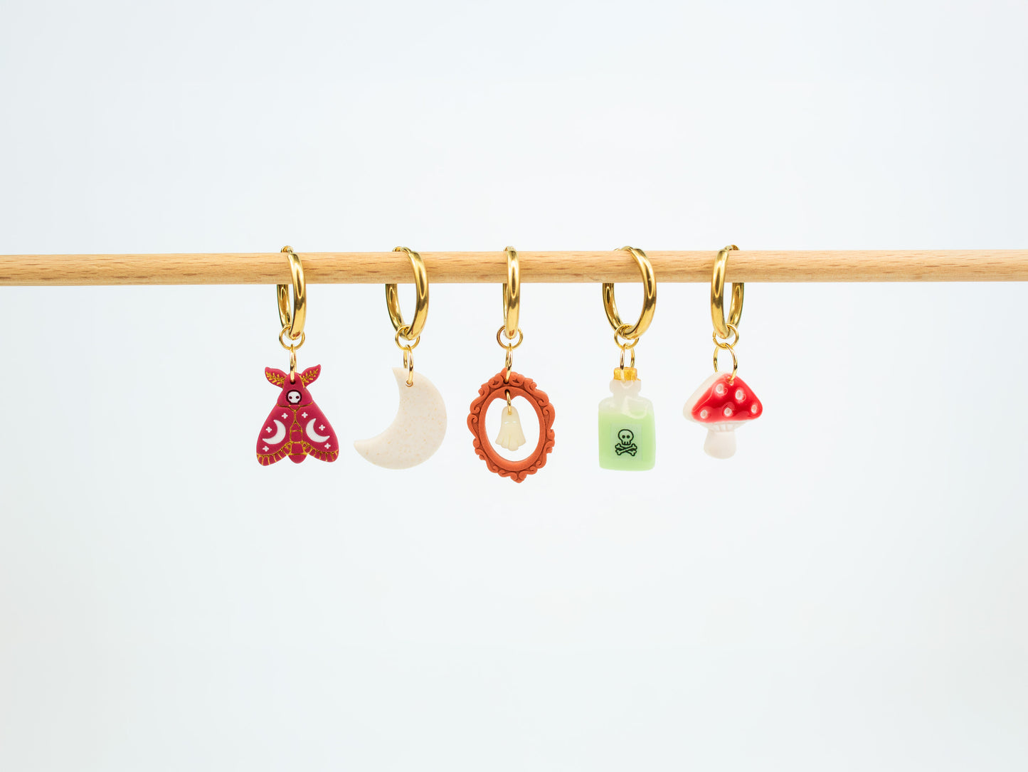 Handmade Halloween and fall earrings displaying interchangeable death moth, moon, glow in the dark ghost, poison bottle, and mushroom charms.