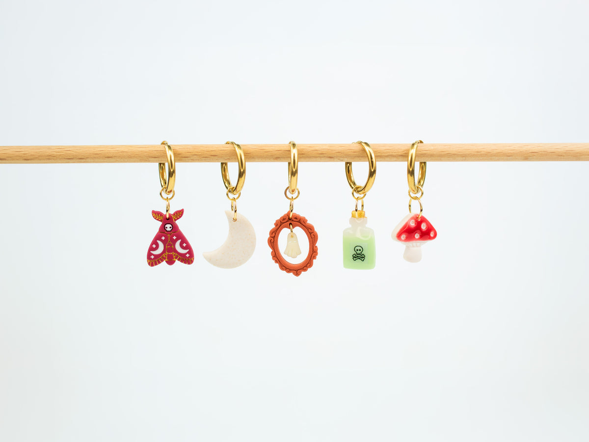 Handmade Halloween and fall earrings displaying interchangeable death moth, moon, glow in the dark ghost, poison bottle, and mushroom charms.
