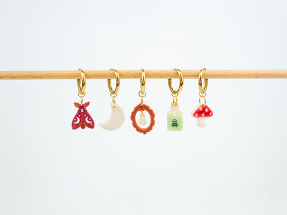 Handmade Halloween and fall earrings displaying interchangeable death moth, moon, glow in the dark ghost, poison bottle, and mushroom charms.