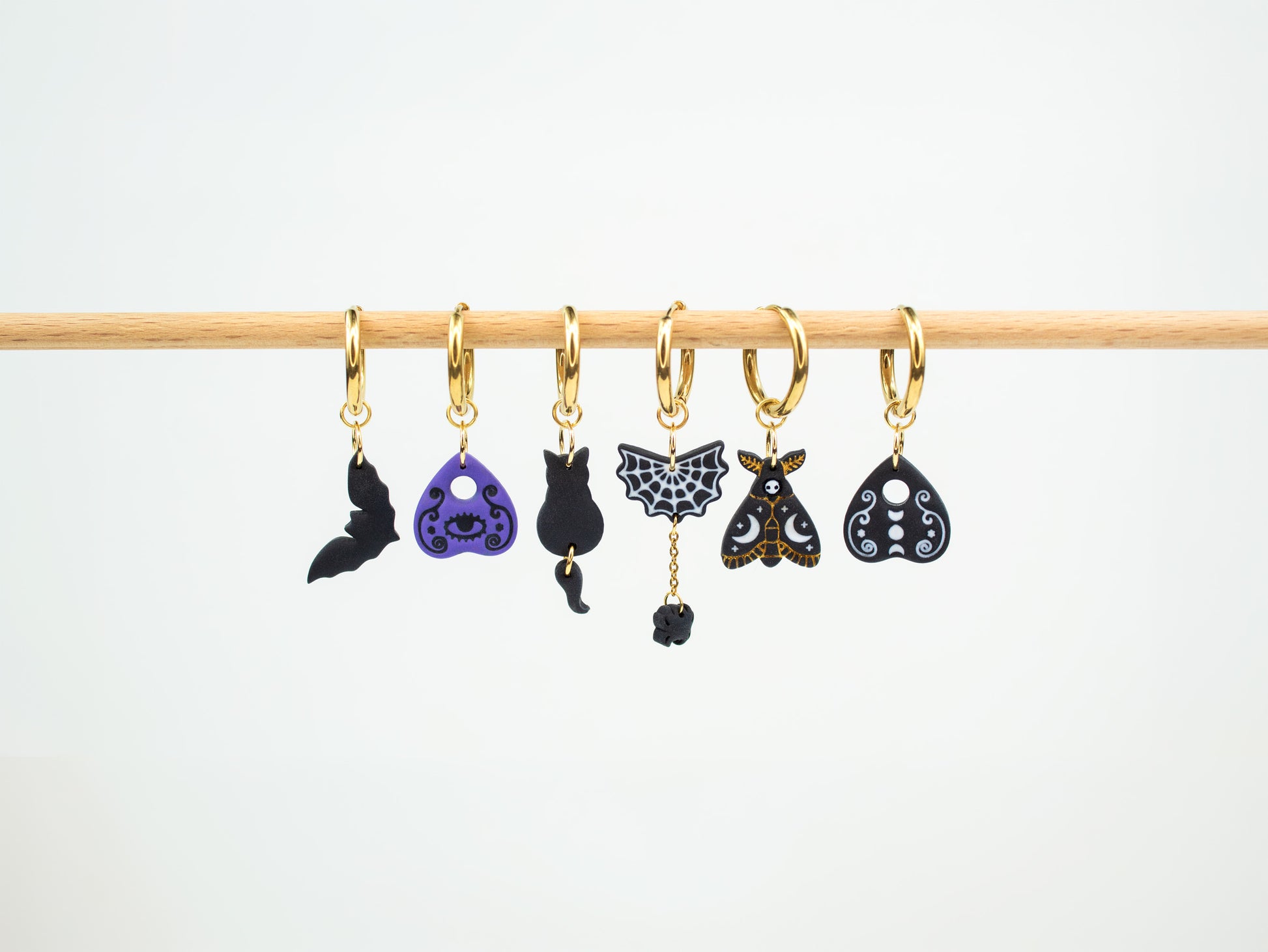 Handmade spooky interchangeable charm hoop earrings featuring a bat, ouija planchettes, black cat, spiderweb, and death moth.