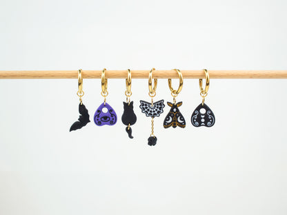 Handmade spooky interchangeable charm hoop earrings featuring a bat, ouija planchettes, black cat, spiderweb, and death moth.