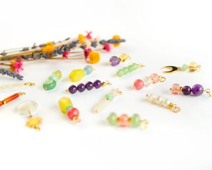 Perspective view of several loose handmade mineral charms with gold stainless steel beads for interchangeable boho-style earrings.