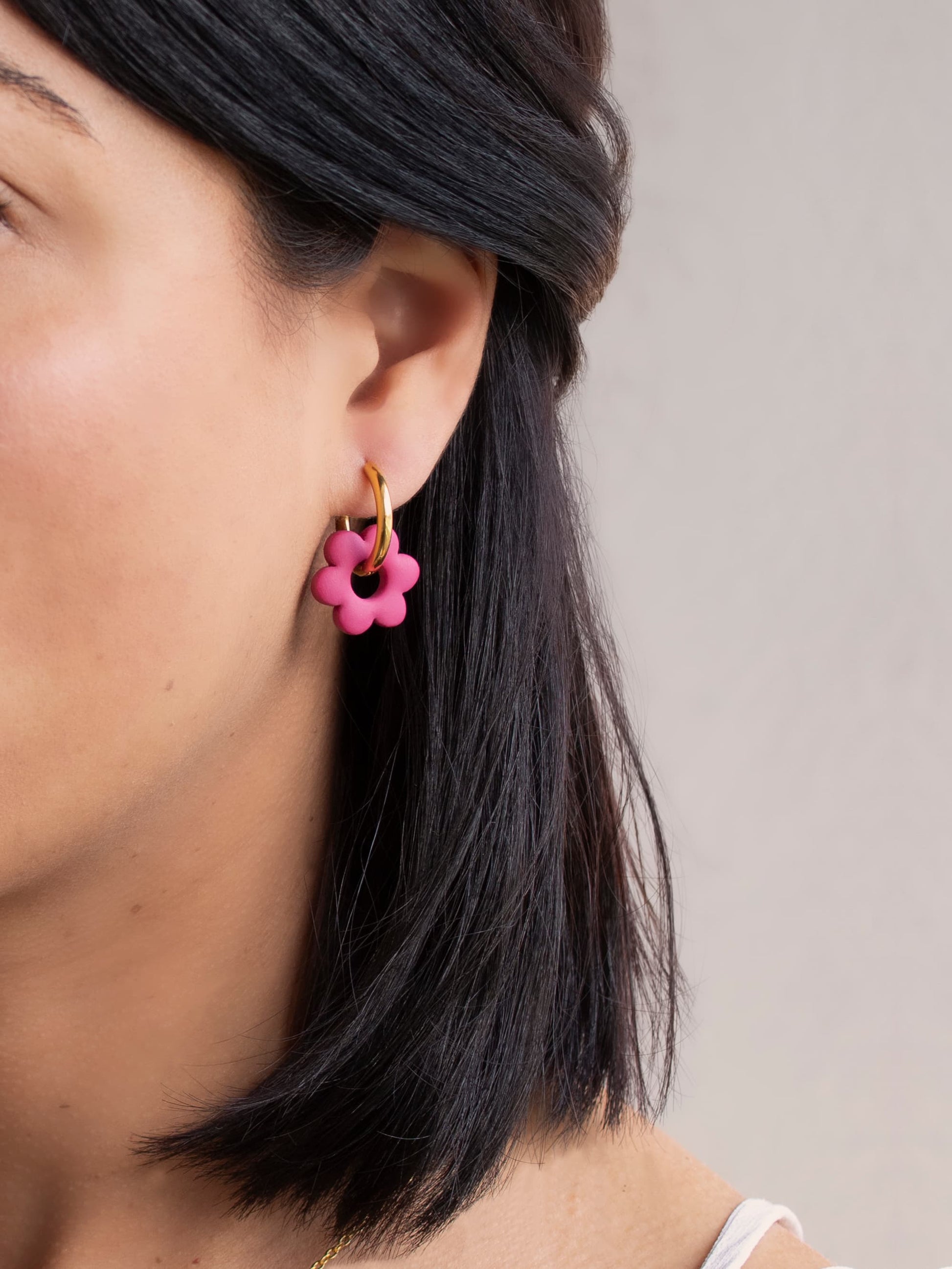 Model wearing gold hoop earrings with pastel flower charms, handmade jewelry