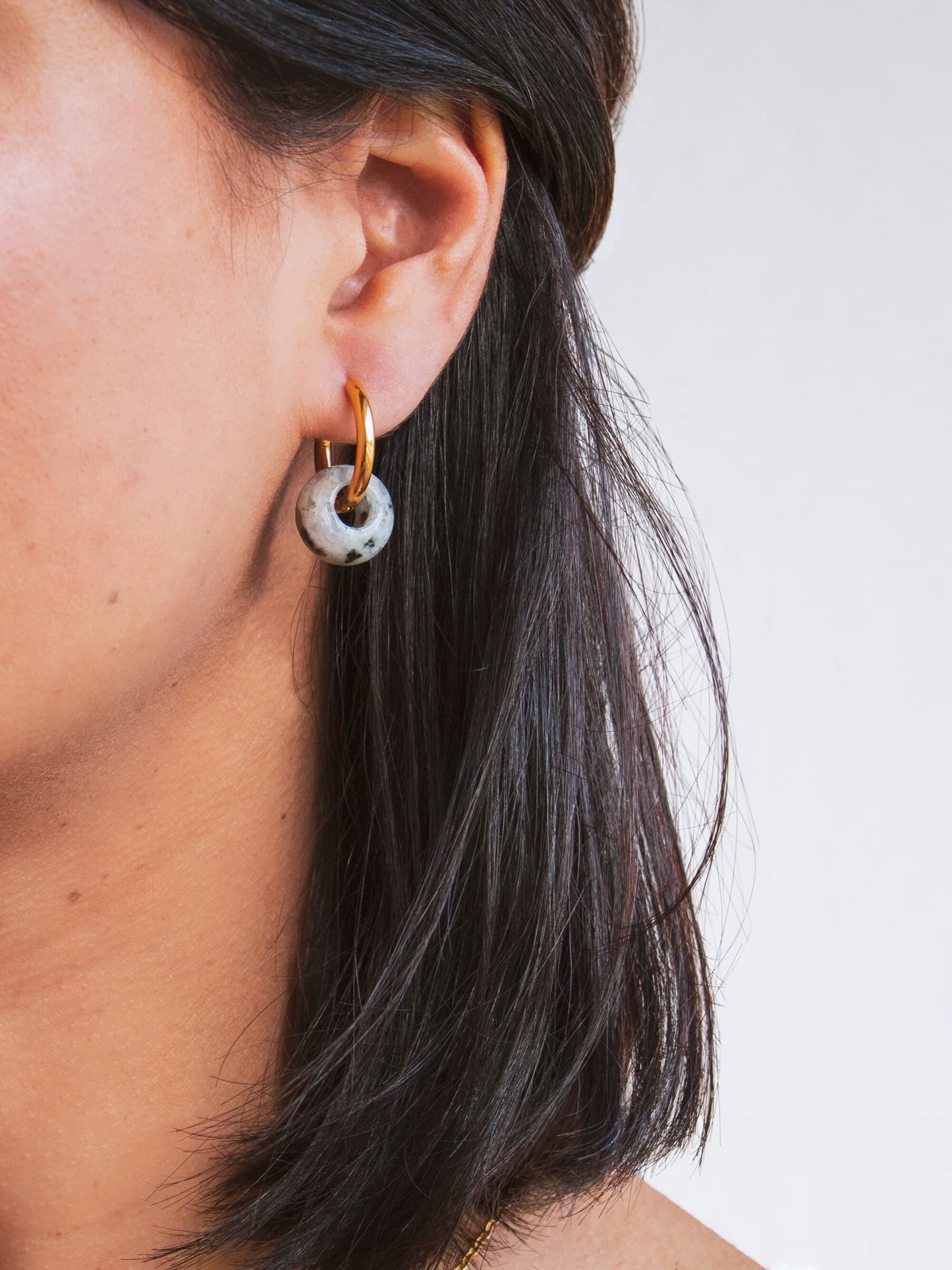 Model shot showing the interchangeable 18K gold plated hoop earring being worn with a single genuine Dalmatian Jasper donut stone charm.