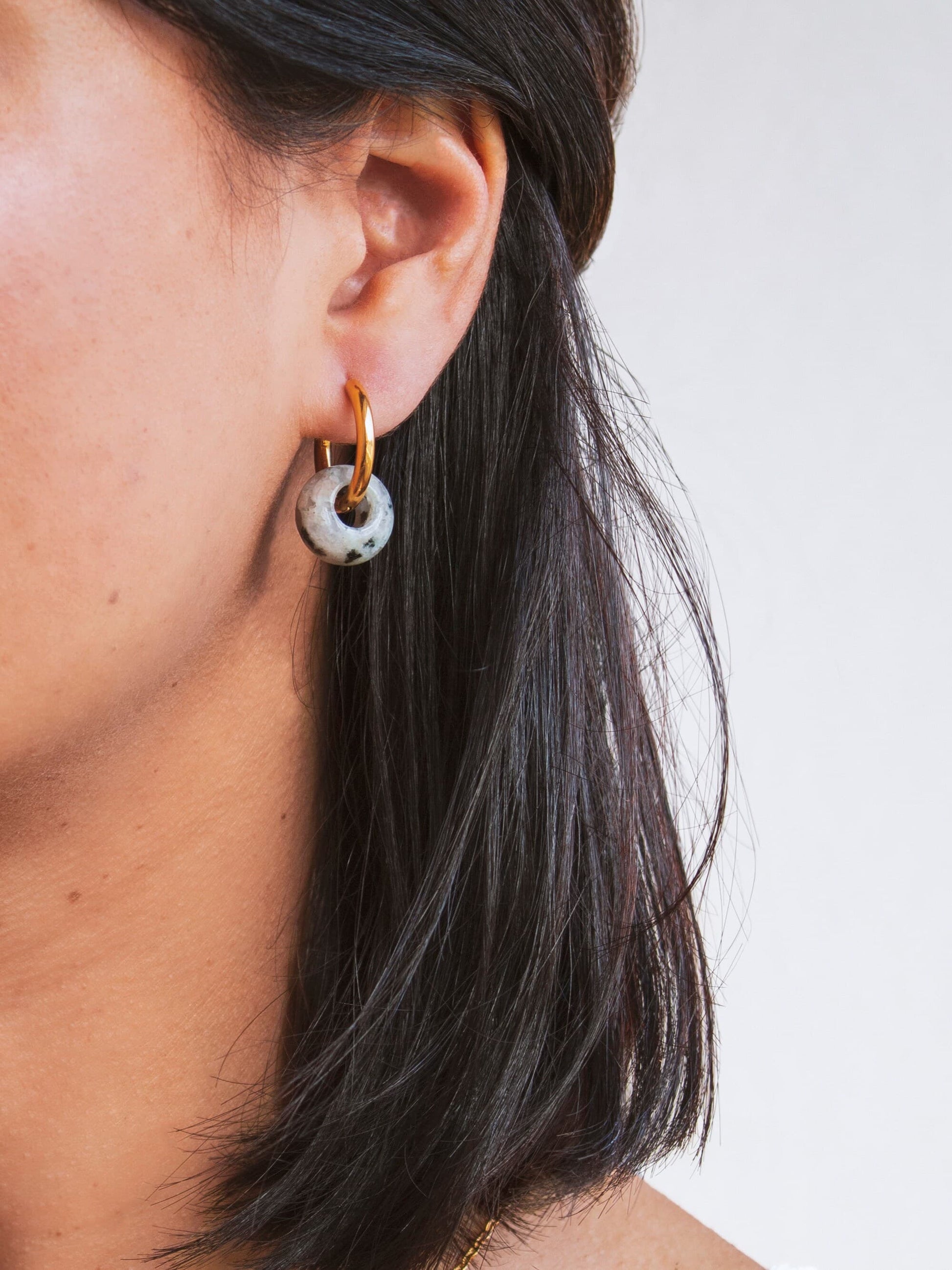Model shot showing the interchangeable 18K gold plated hoop earring being worn with a single genuine Dalmatian Jasper donut stone charm.