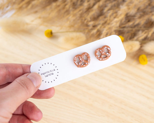  Handmade pretzel stud earrings displayed on a branded card, crafted from lightweight hypoallergenic clay.