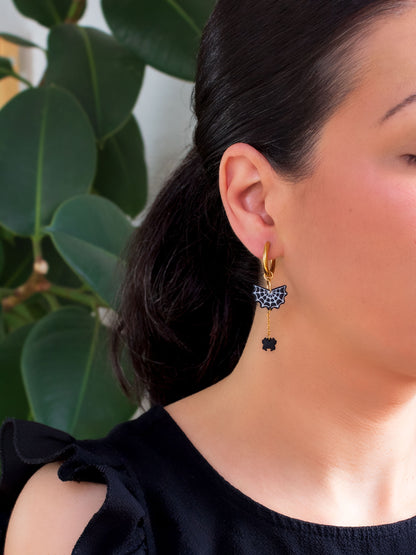 Woman wearing a spooky handmade spiderweb charm hoop earring from an interchangeable witchy jewelry collection.
