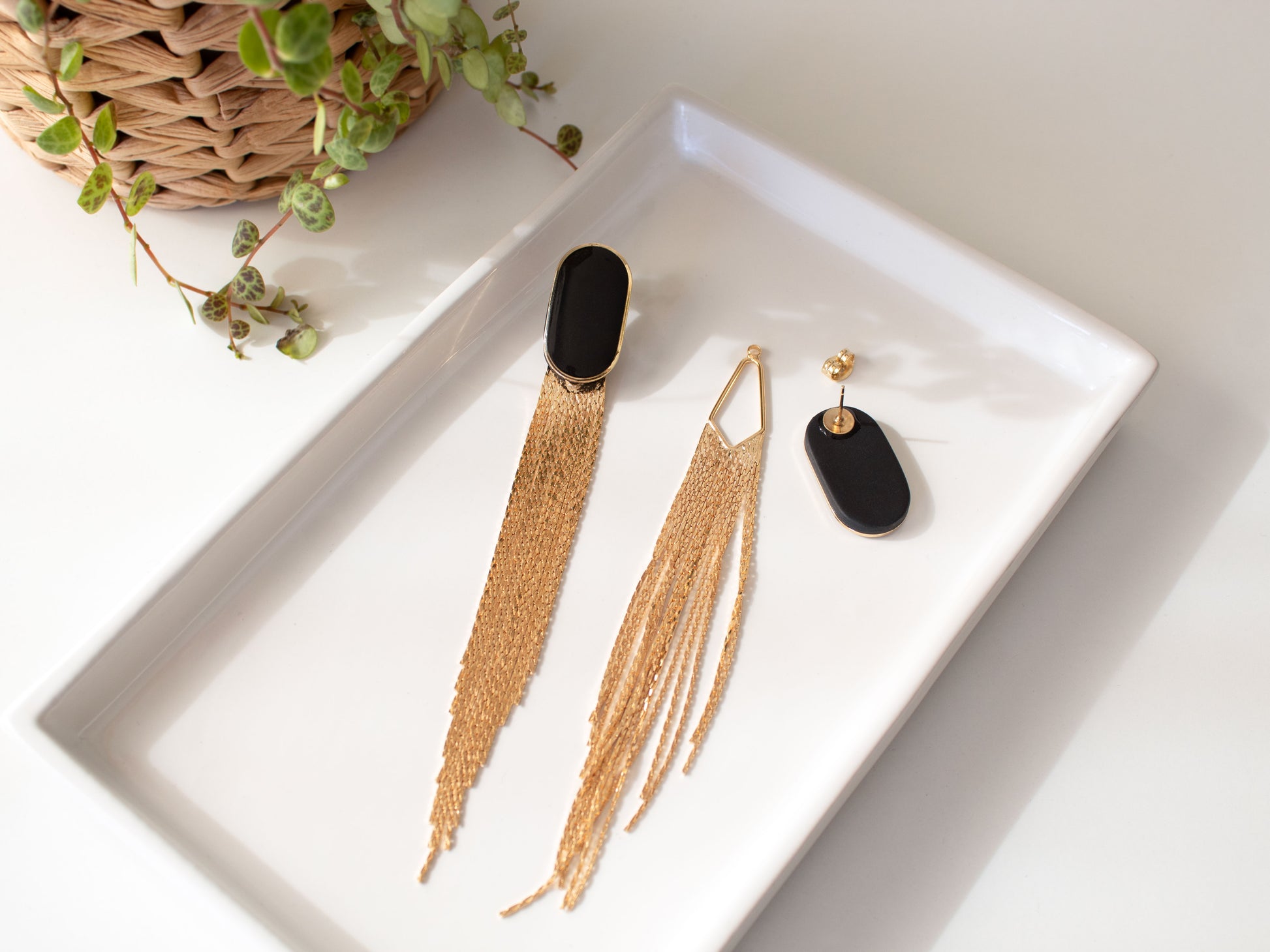 Two in one black earrings showing stud and gold chain fringe on tray