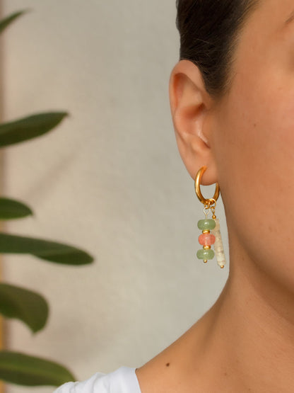 Close-up of a model wearing two natural stone charms combined on a single gold stainless steel hoop earring.