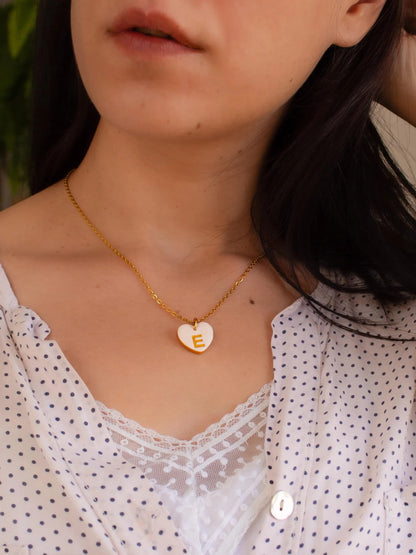 Model wearing personalized heart initial necklace in white blouse